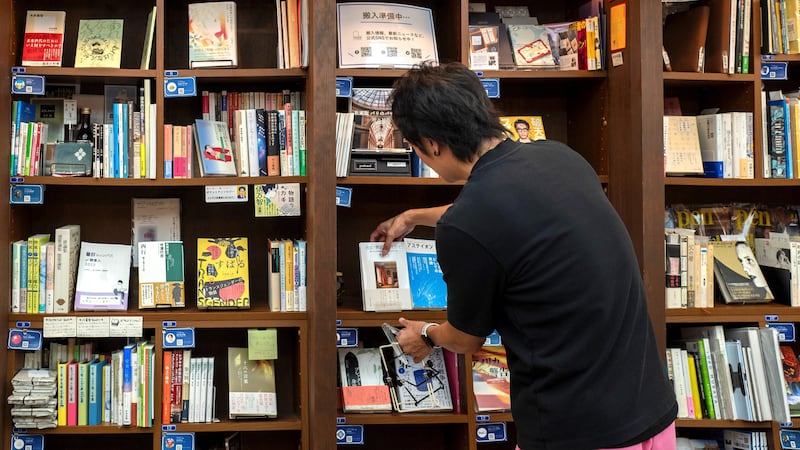 This photo taken on August 1, 2024 shows Rokurou Yui, president of book review site All Reviews and president of three shelf-sharing bookstores, working at his bookstore in Tokyo's Kanda Jimbocho district, one of the world's largest 