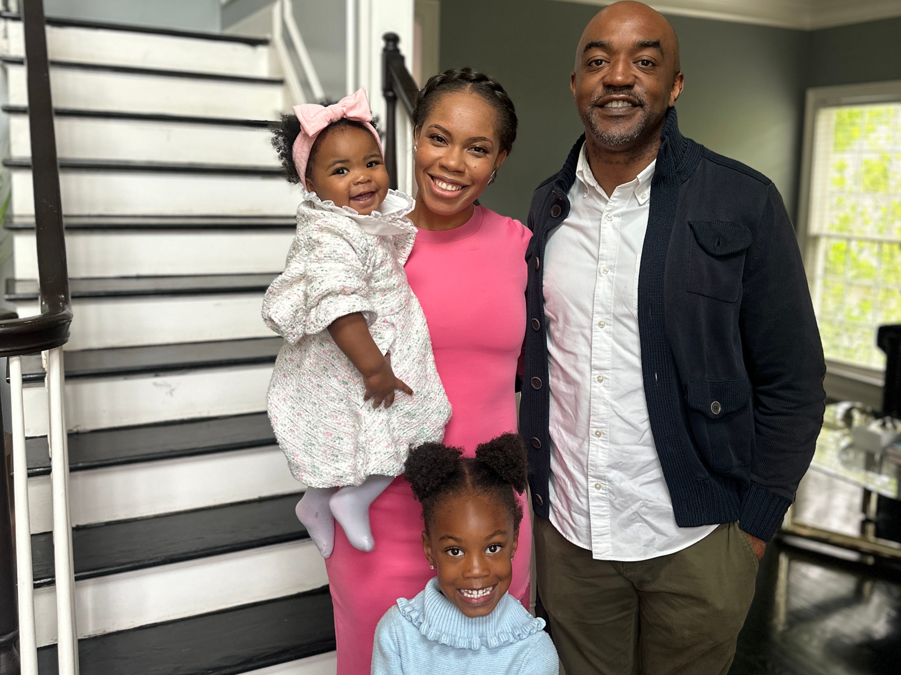 A family of four standing in front of a staircase