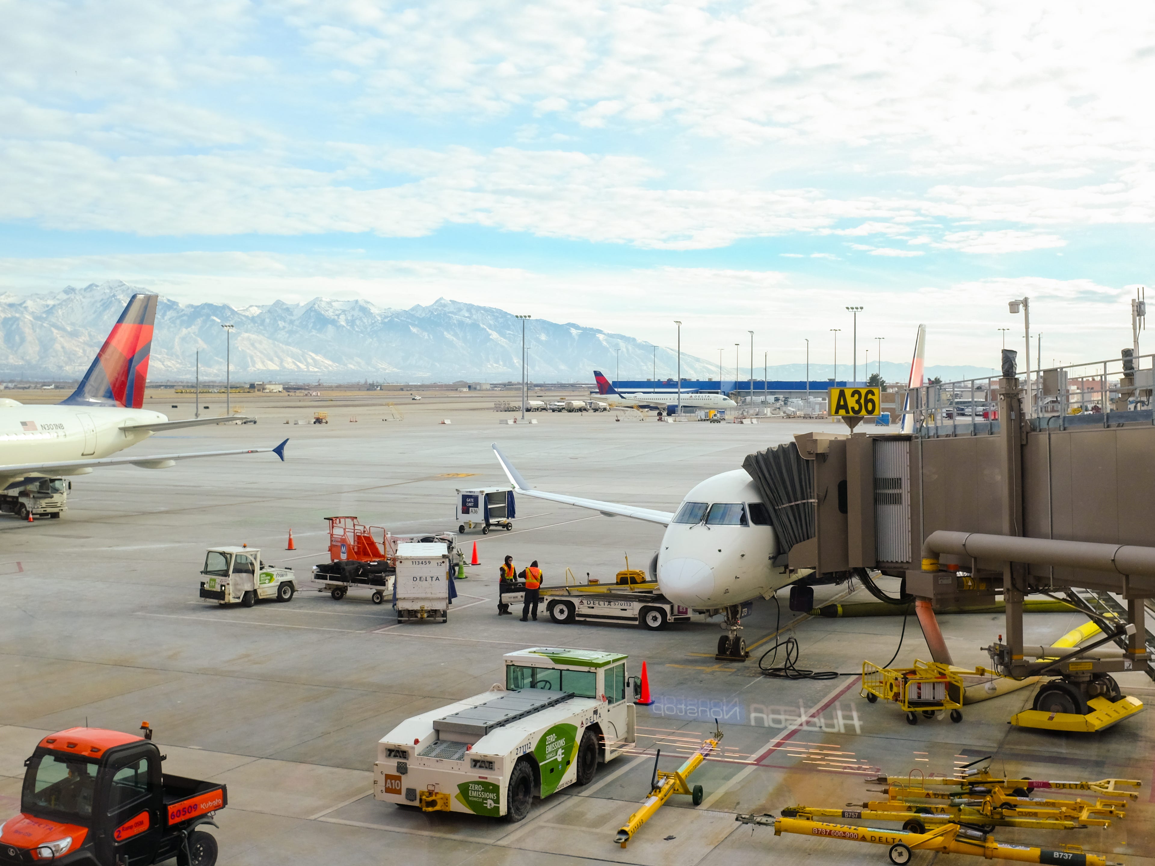 A Delta plane is parked at a gate with mountains in the background