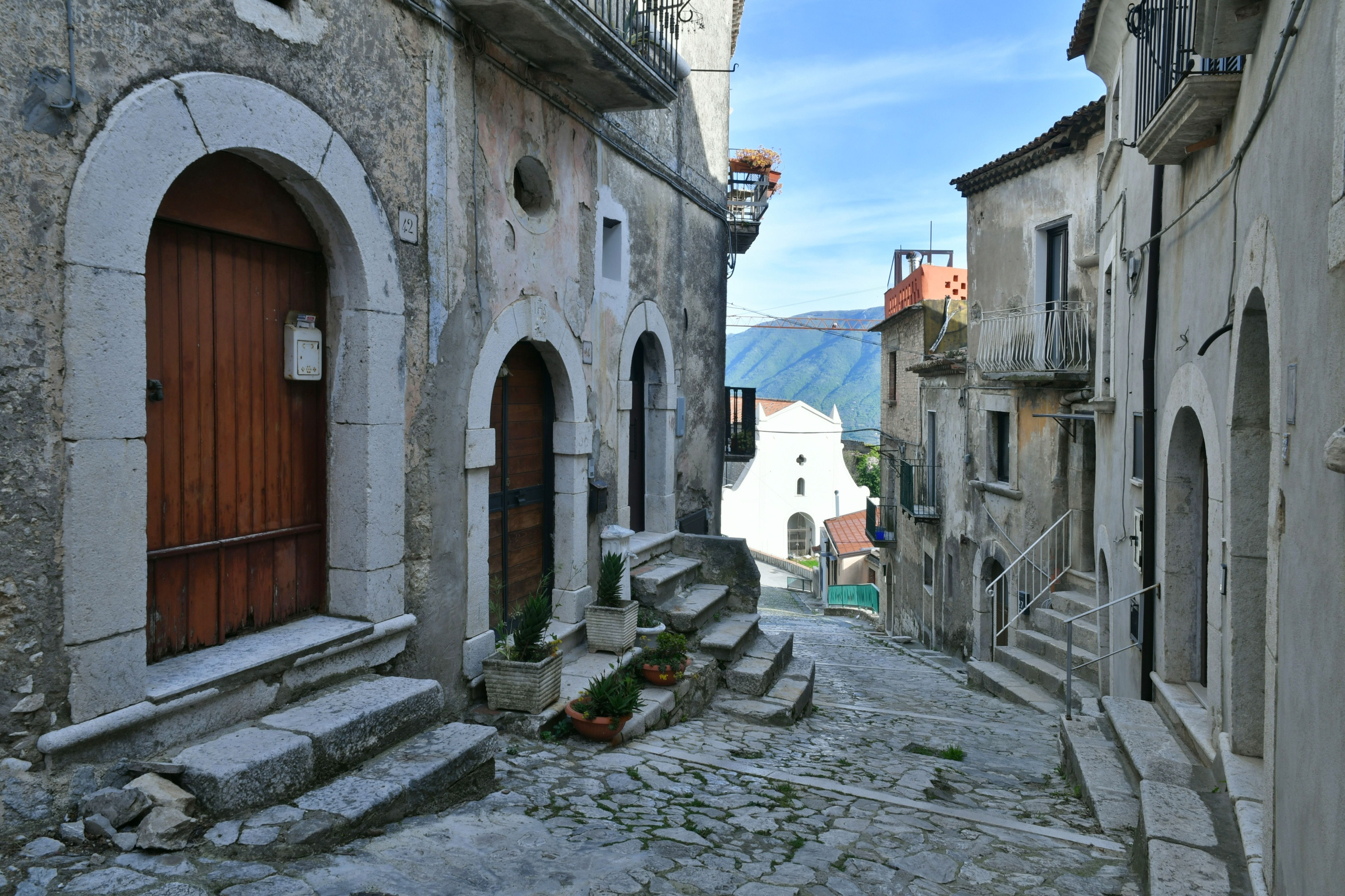 A cobblestone alleyway between old homes in Italy.