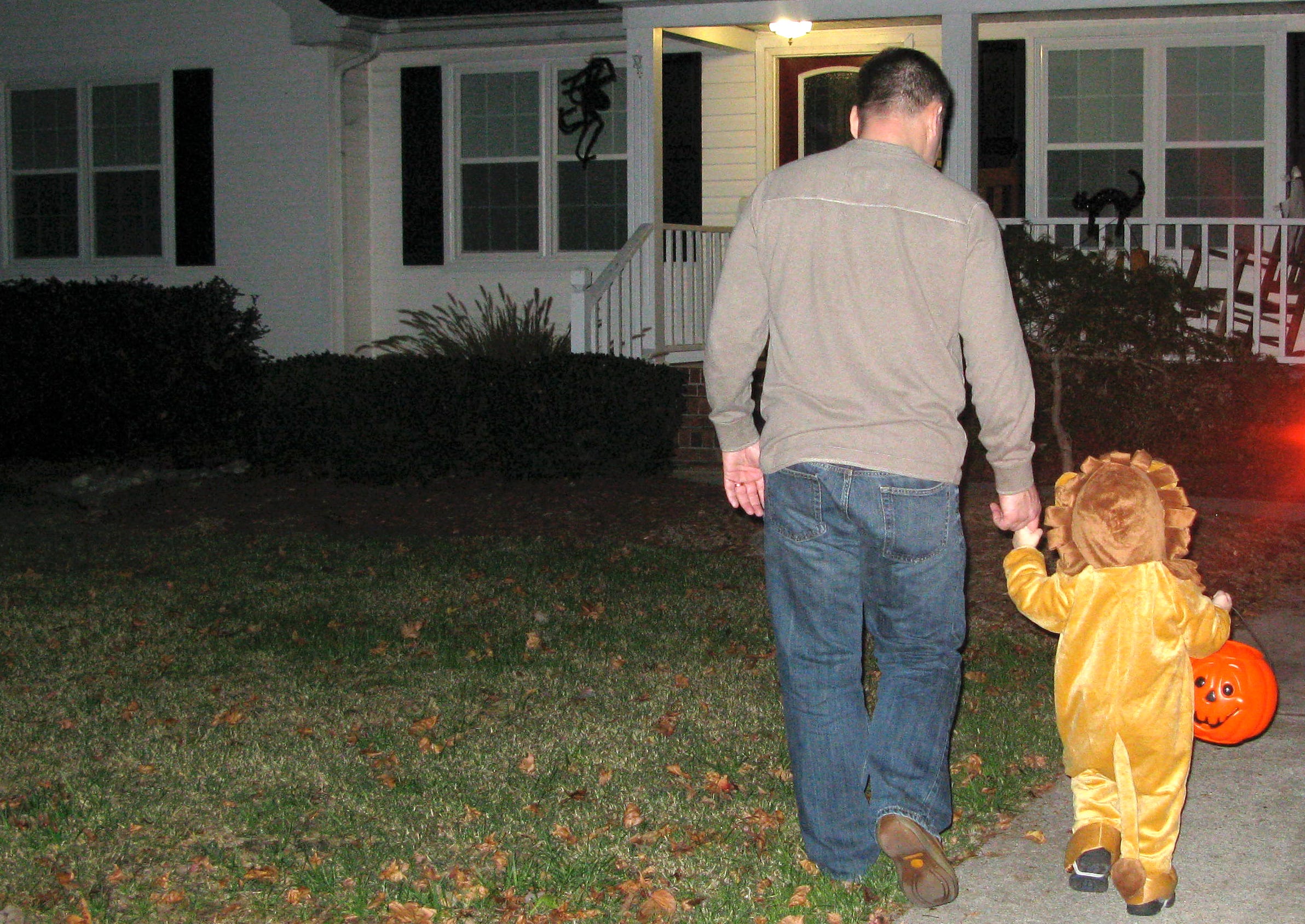 The author's husband trick-or-treating with one of their sons, dressed as a lion, in 2011.