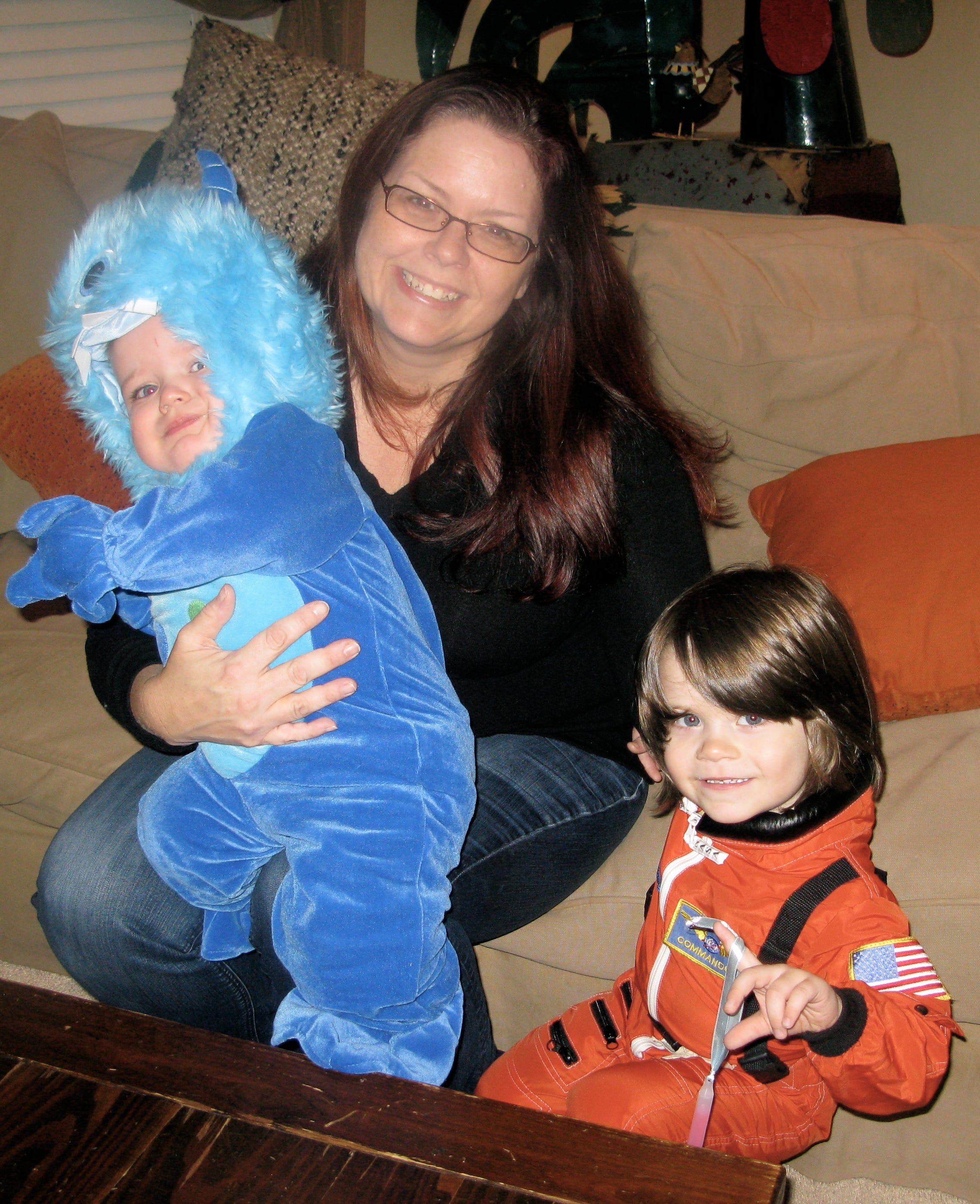 The author with her two kids on Halloween, sitting on the couch. The two boys are dressed in costumes.