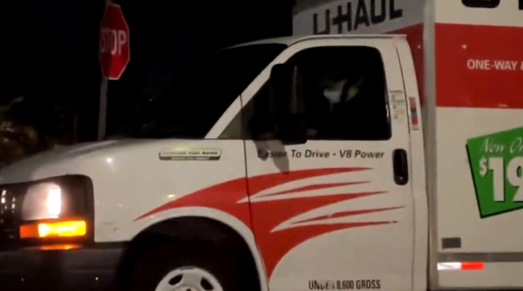 A U-Haul truck at night, with a stop sign barely visible behind it.