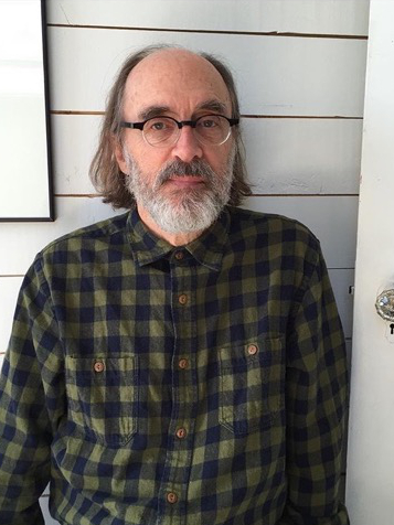 Man with long hair and beard wearing glasses and a plaid shirt.
