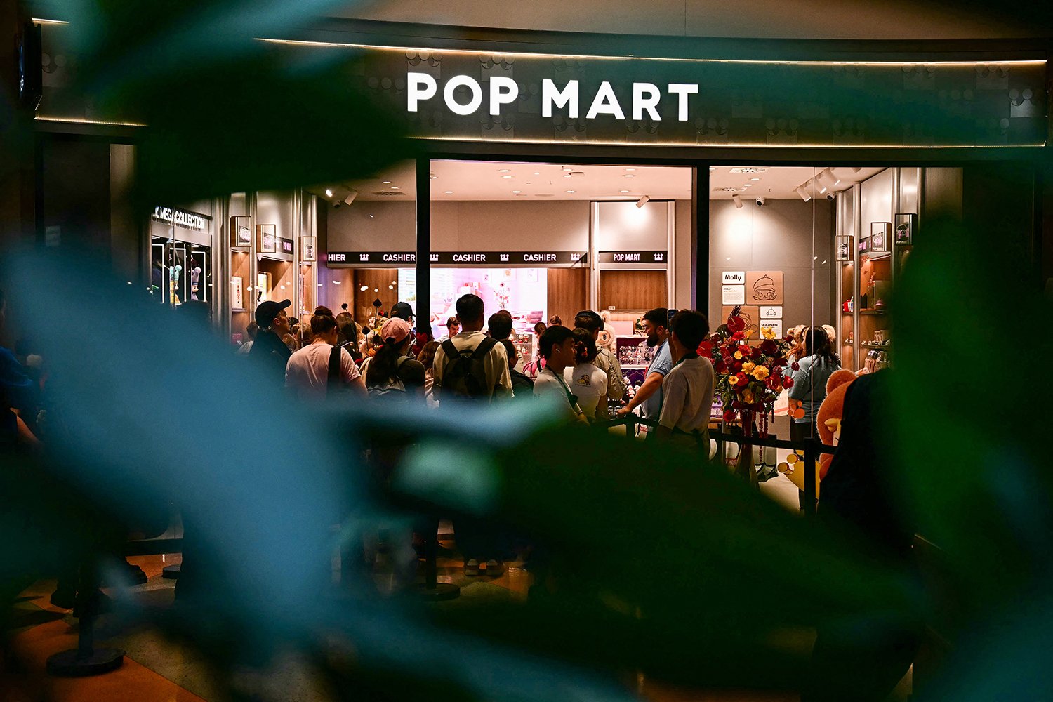 People wait in line to visit a new Pop Mart store at night.