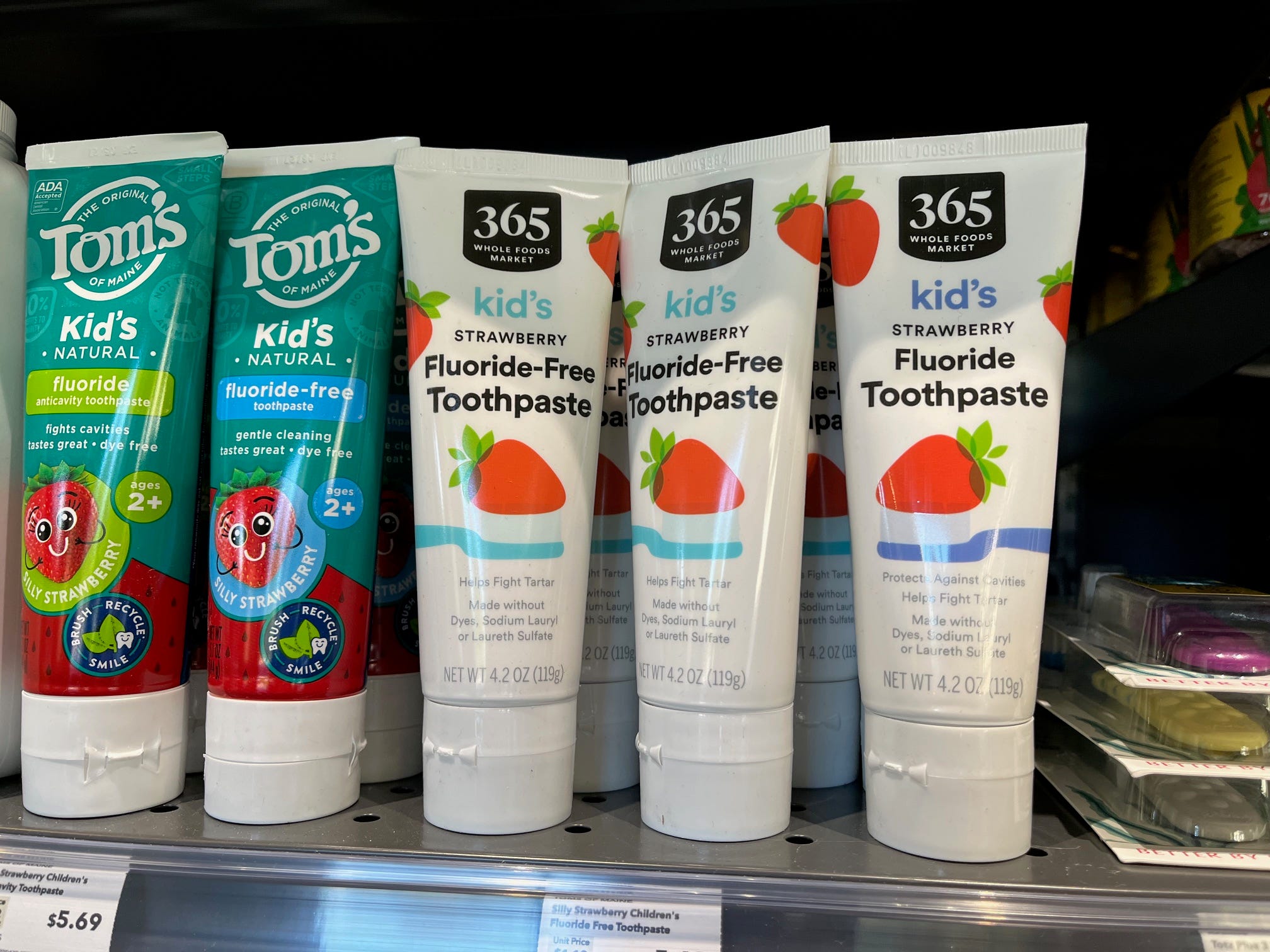 Tubes of toothpaste for kids made under Whole Foods' 365 store brand sit on a shelf next to similar products from Tom's of Maine at a Whole Foods Daily Shop store.