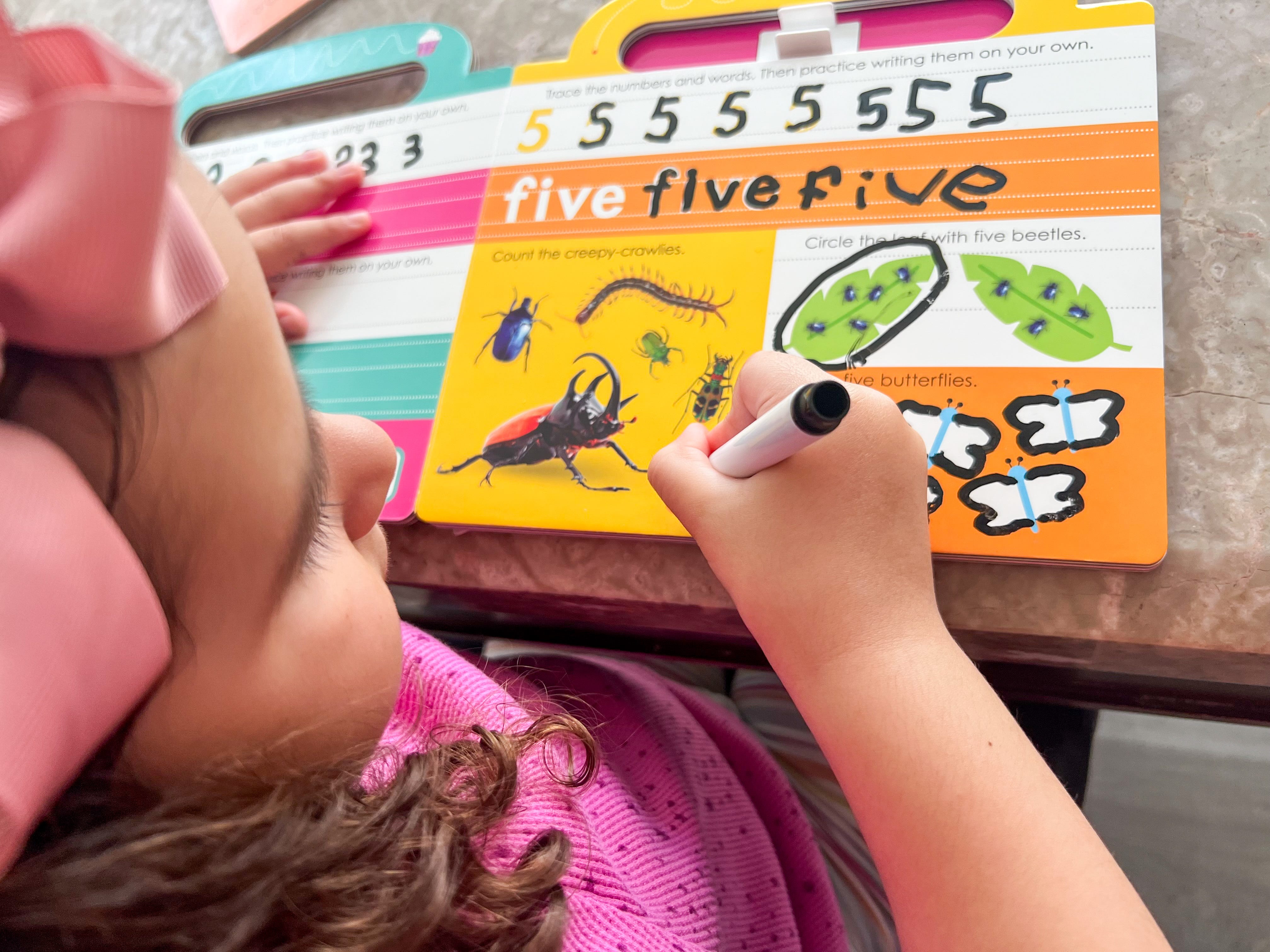 Tiffany Tuttle's daughter writing on workbooks while being homeschooled