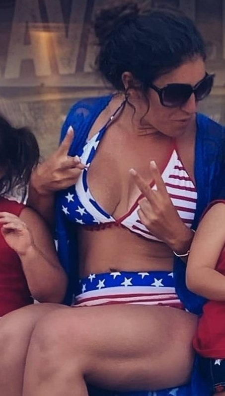 Danielle Bellomo in a star-spangled bikini, holding up a peace sign.