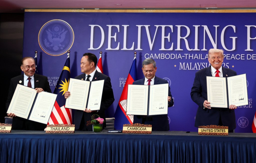 Four world leaders holding up documents at the 47th ASEAN Summit in Kuala Lumpur to sign a ceasefire deal between Cambodia and Thailand.