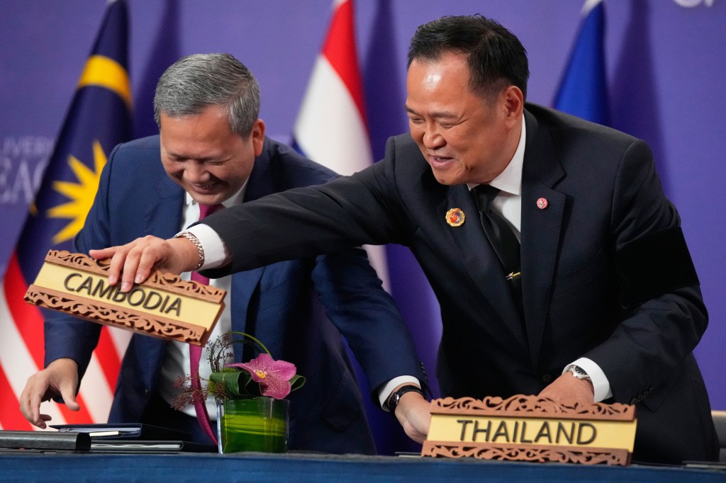 Cambodian Prime Minister Hun Manet and Thailand's Prime Minister Anutin Charnvirakul switch country signs.