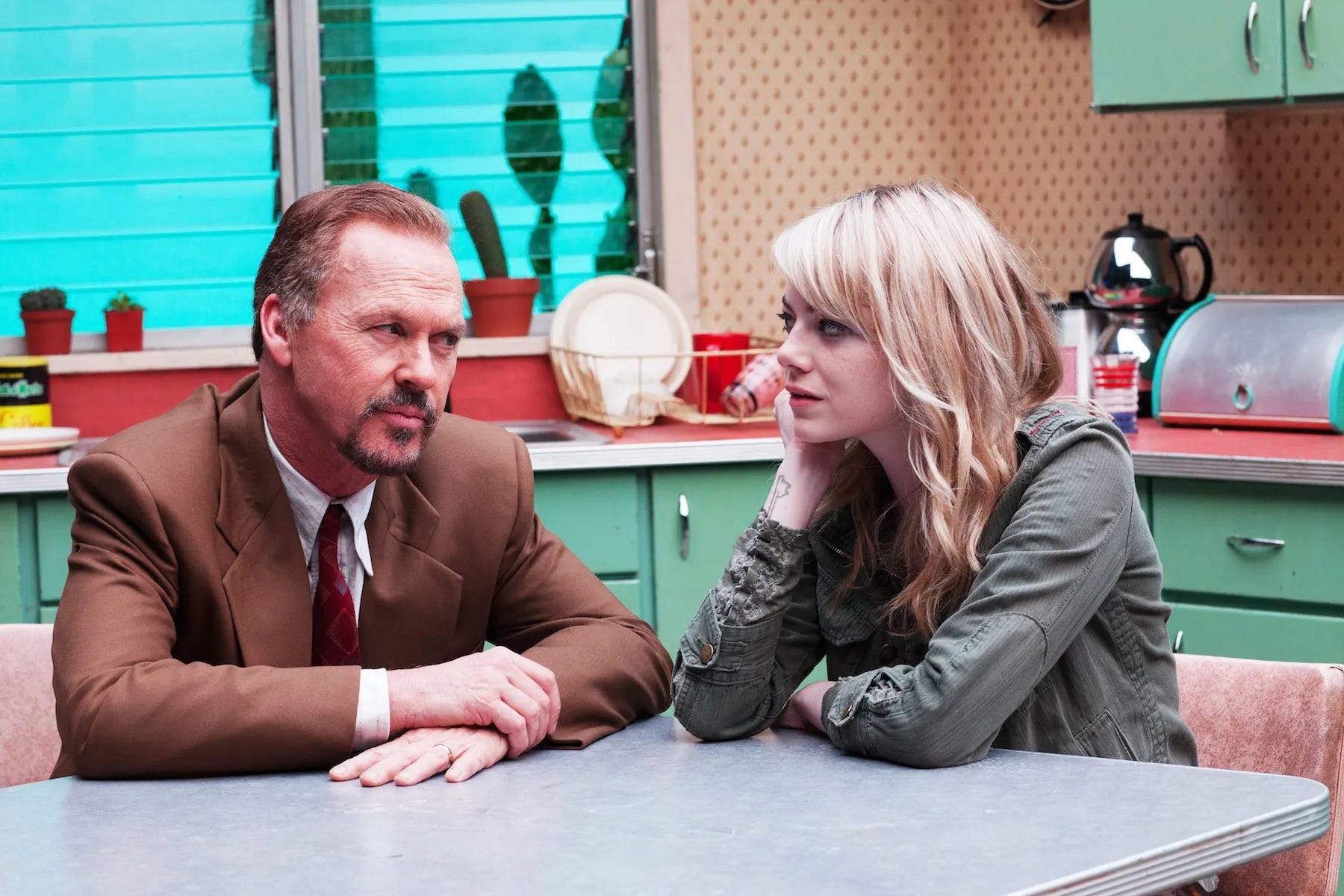 Michael Keaton and Emma Stone sitting at a table in the movie Birdman