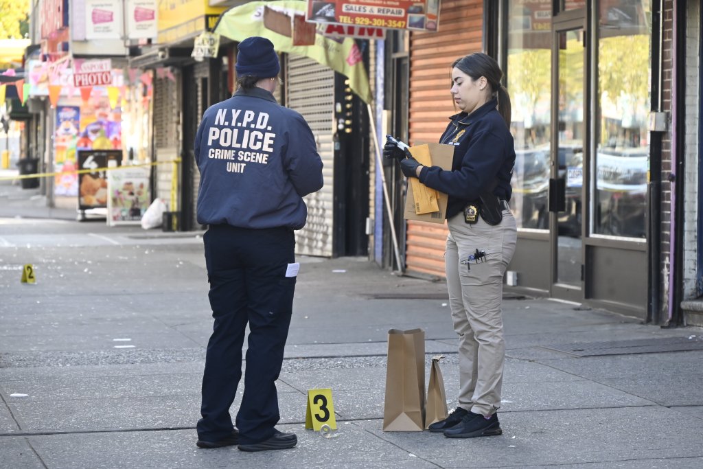 Two members of the NYPD Crime Scene Unit collect evidence at a crime scene on 28 East Kingsbridge Road.