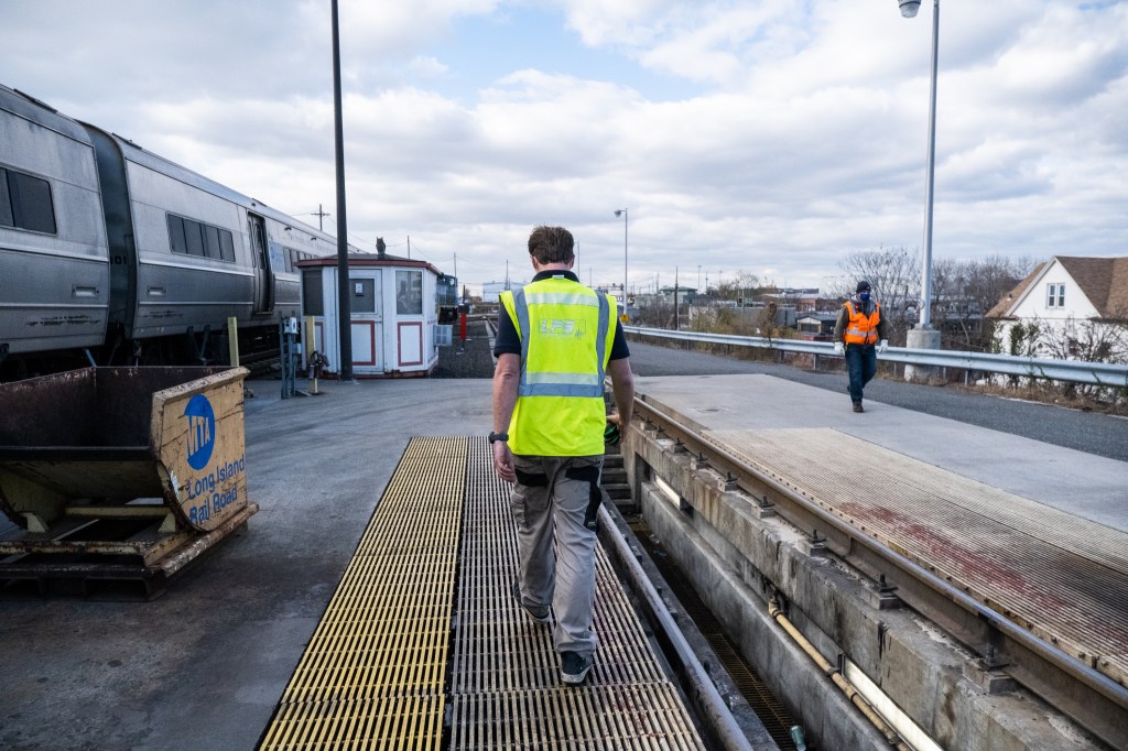 Harm Medendorp of LPS walks along Long Island Rail Road tracks next to a train.