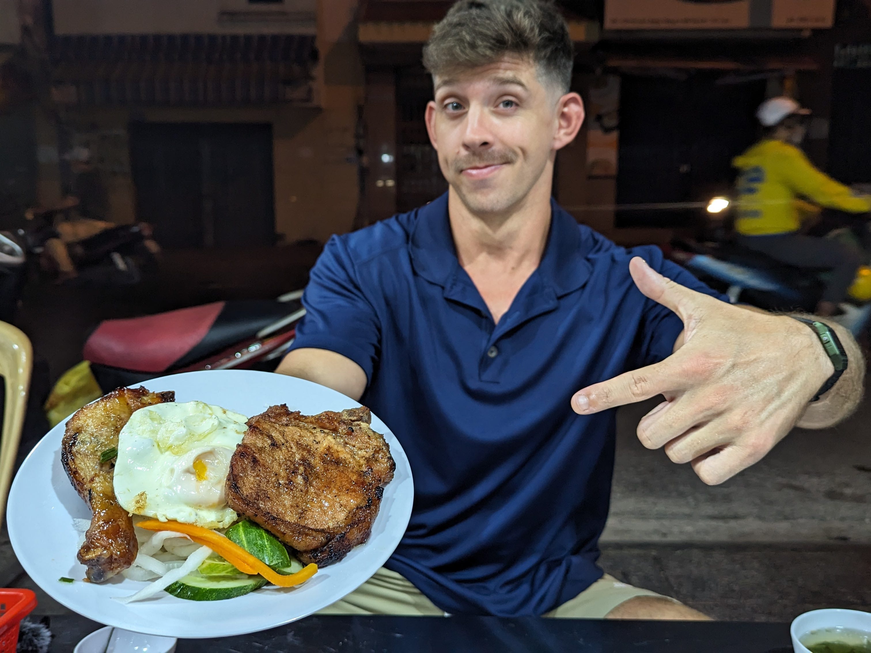 A man holding up a plate of rice and meat in Vietnam.