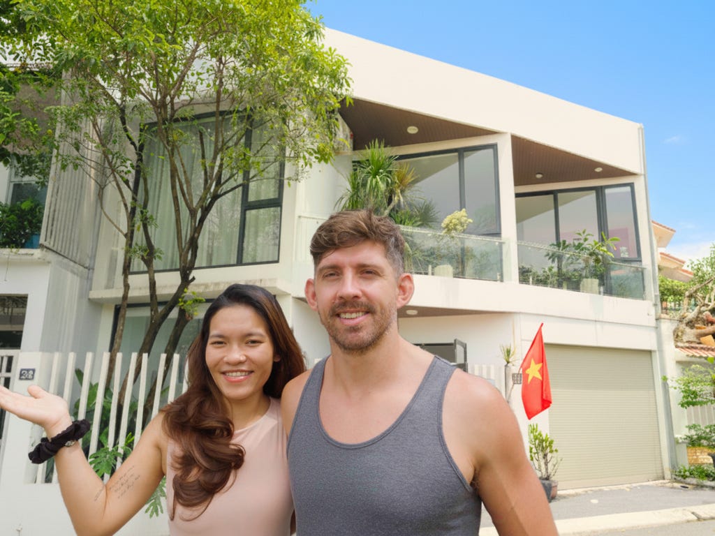 A couple posing for a photo in front of their house.