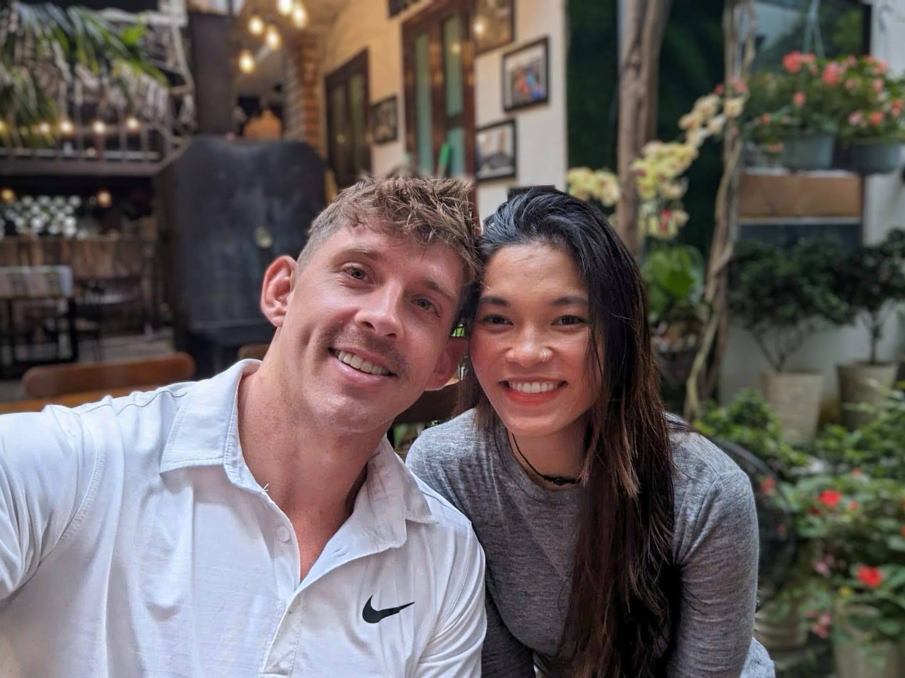 A couple posing for a photo in front of a stall.
