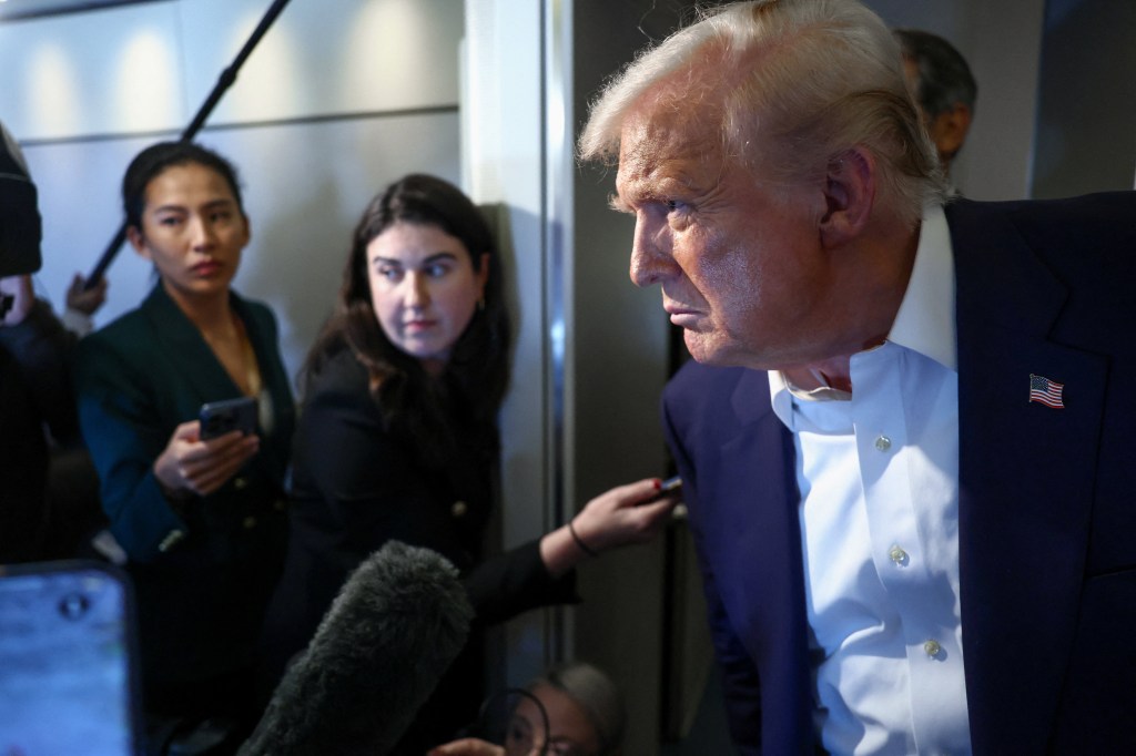 U.S. President Donald Trump speaks to reporters aboard Air Force One.