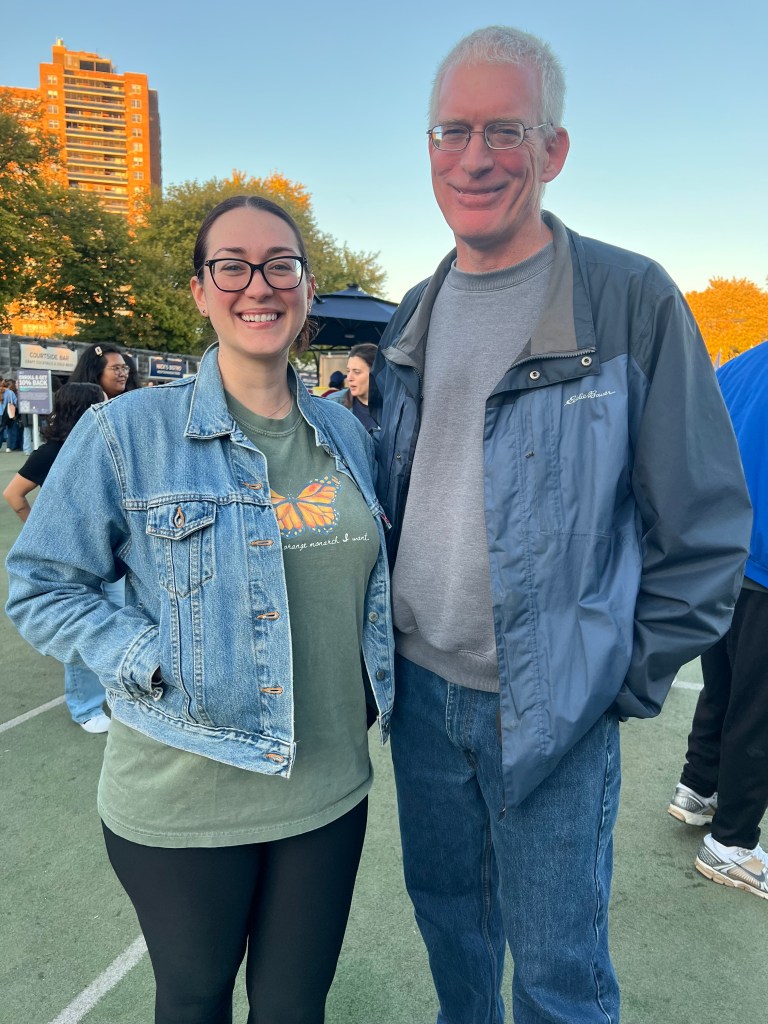 Rebecca and her father John, a retired Federal agent, smiling at a Democratic Socialist rally in Queens.