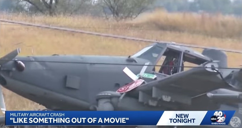A military aircraft crash-landed, resting on a grassy field, its propeller blades bent.