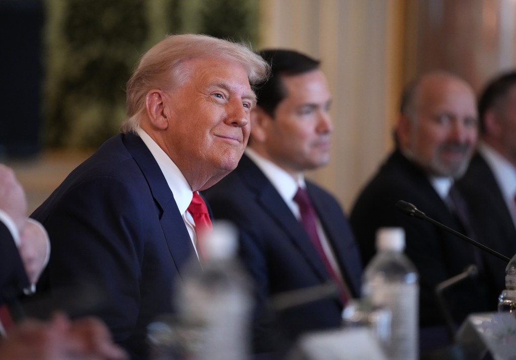 President Donald Trump sits at a table with other officials.
