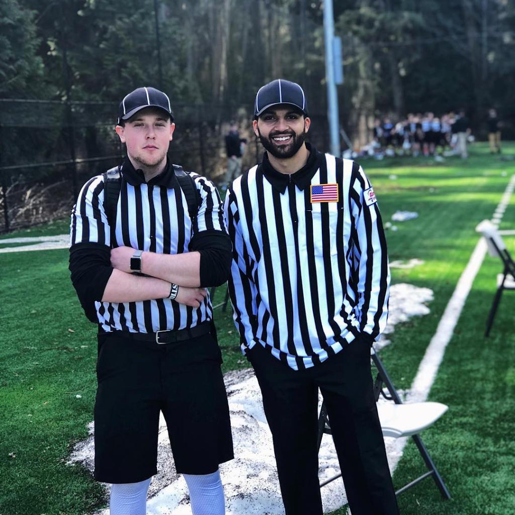 Two men in referee uniforms standing on a sports field.