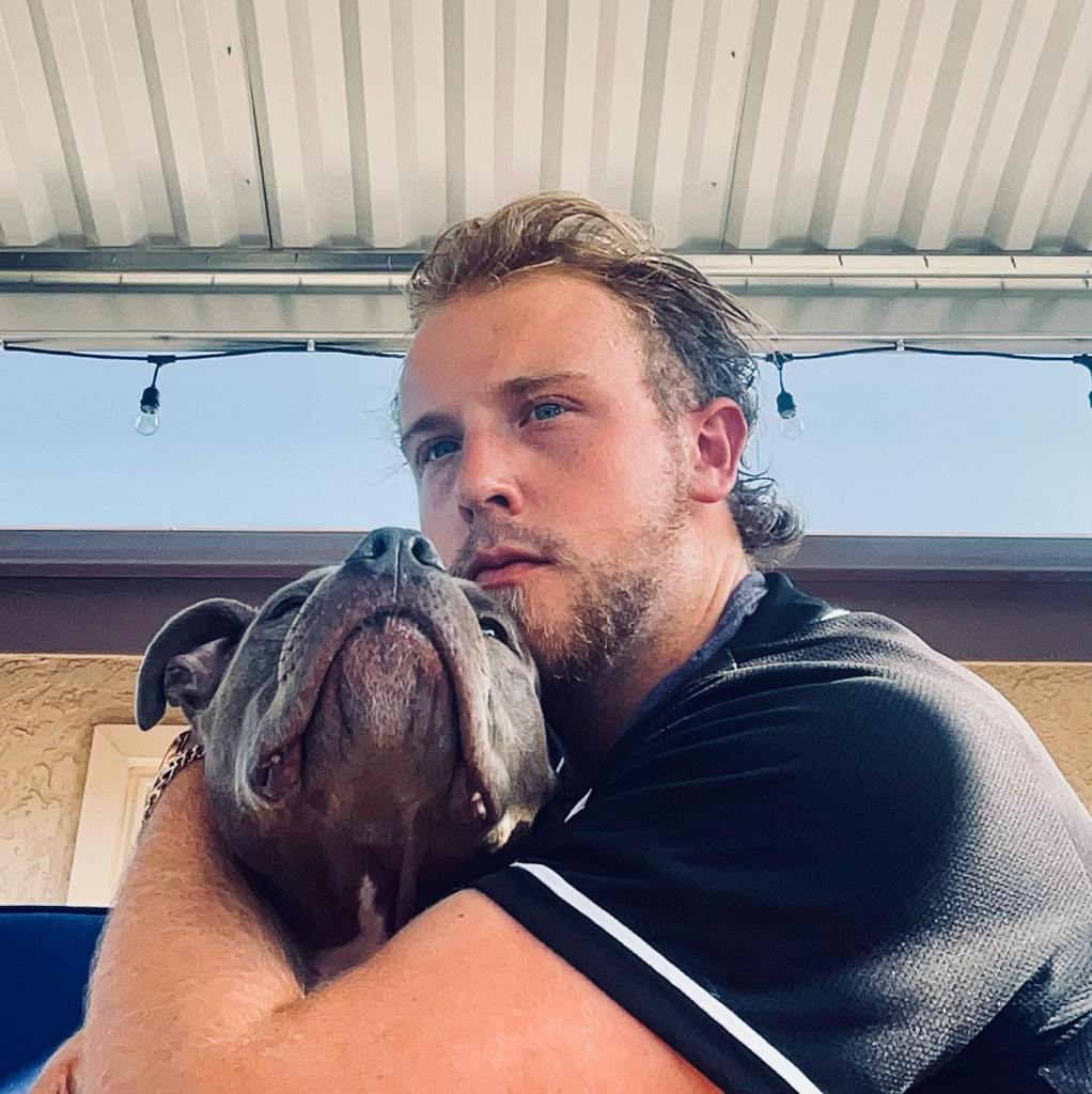 Matthew Cohn embracing a gray pit bull.