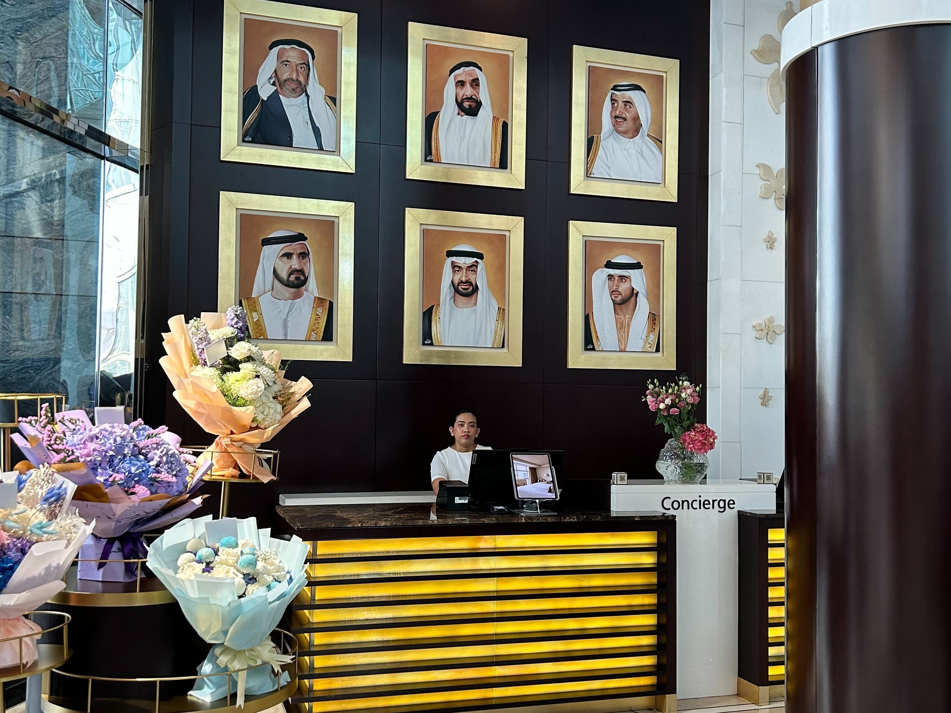 Six portraits hang over the desk of a hotel receptionist