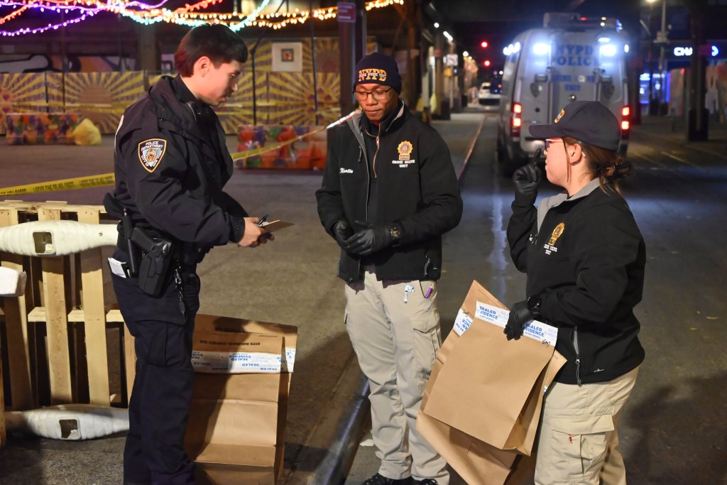Investigators collecting evidence bags at a crime scene.