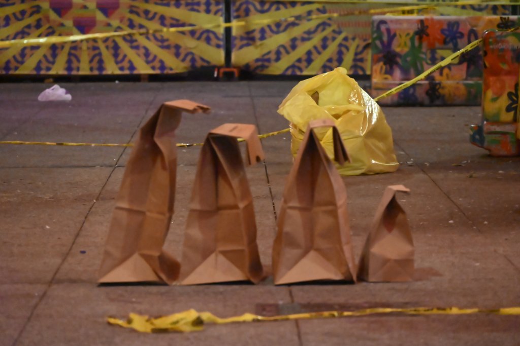 Police and investigators gathered at a crime scene under an overpass with strung lights, where a deceased woman was found on a sidewalk on East 124 Street and Park Avenue.