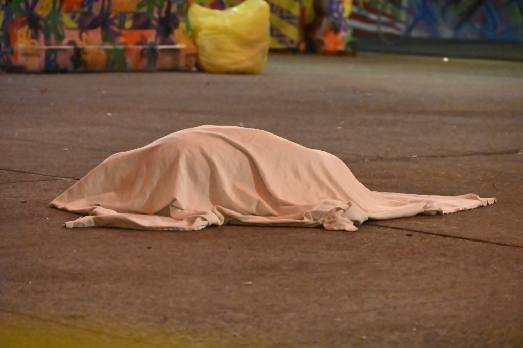 Body covered with a sheet on a sidewalk.
