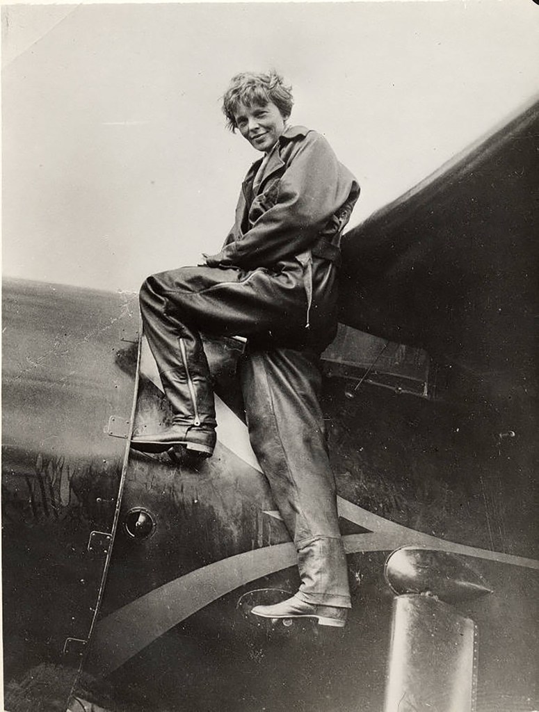 Amelia Earhart sitting on the wing of an aircraft.