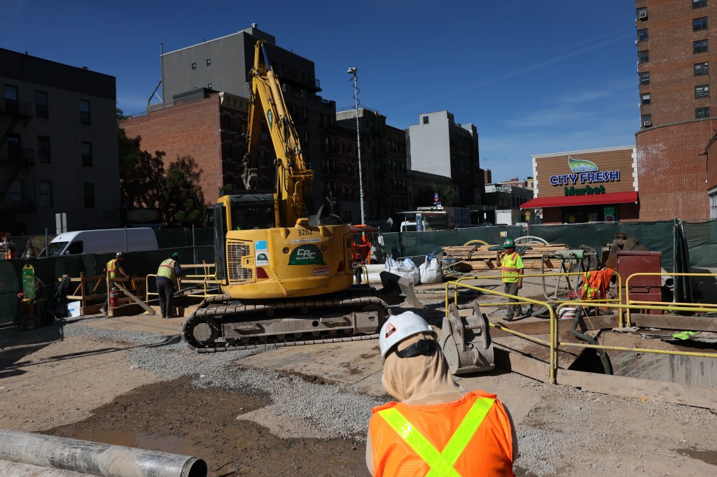 Construction site for the Second Avenue Subway in New York City with an excavator and workers.