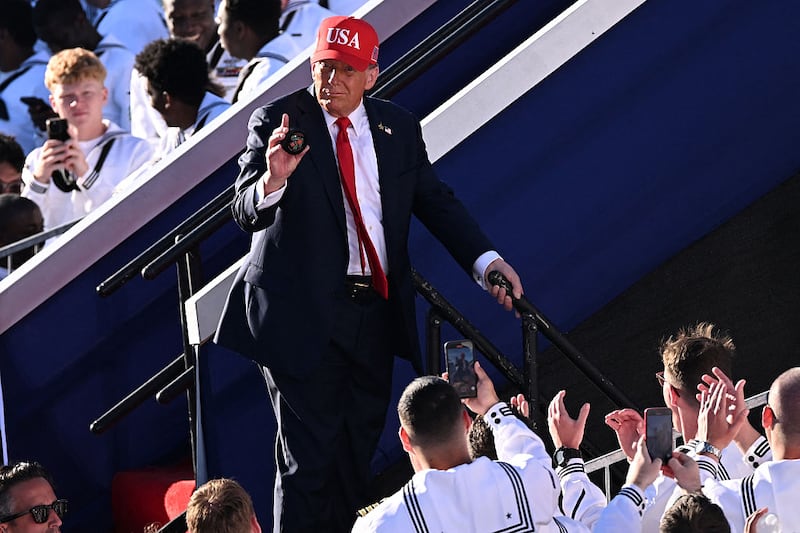 US President Donald Trump holds up an object after delivering remarks during the US Navy's 250th anniversary celebration,
