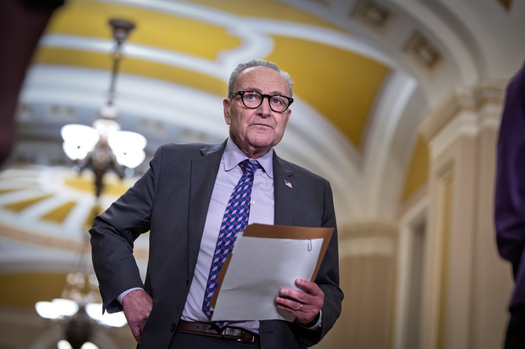 Senate Minority Leader Chuck Schumer holding papers before speaking with reporters.
