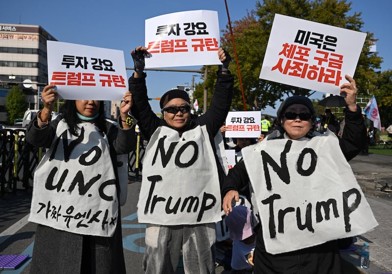 South Korean protesters wearing signs reading