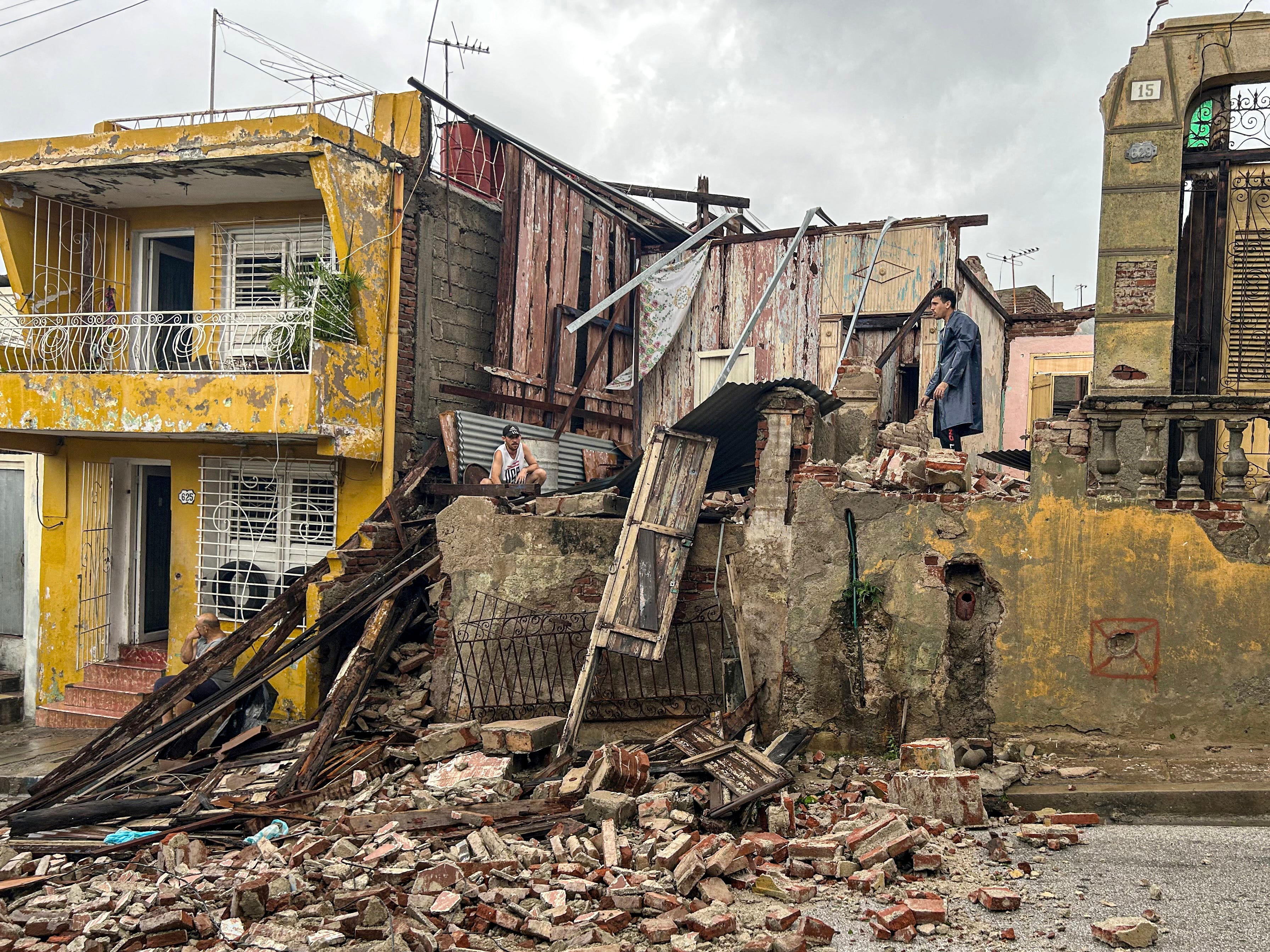 Men salvage belongings from the rubble of her their home after it collapsed during Hurricane Melissa's passage through Santiago de Cuba, Cuba, on October 29, 2025