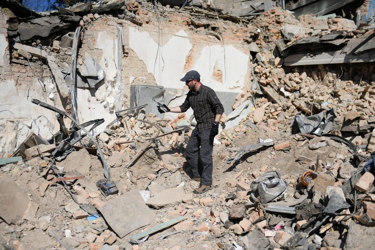 Brian Castner standing in a pile of rubble that is the remnants of a demolished building.