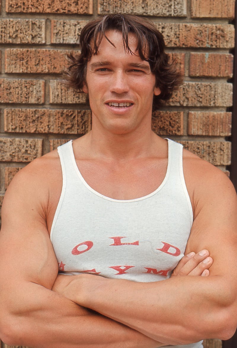 A classic photo of Arnold Schwarzenegger wearing a similarly muscle-baring Gold's Gym tank in 1977.