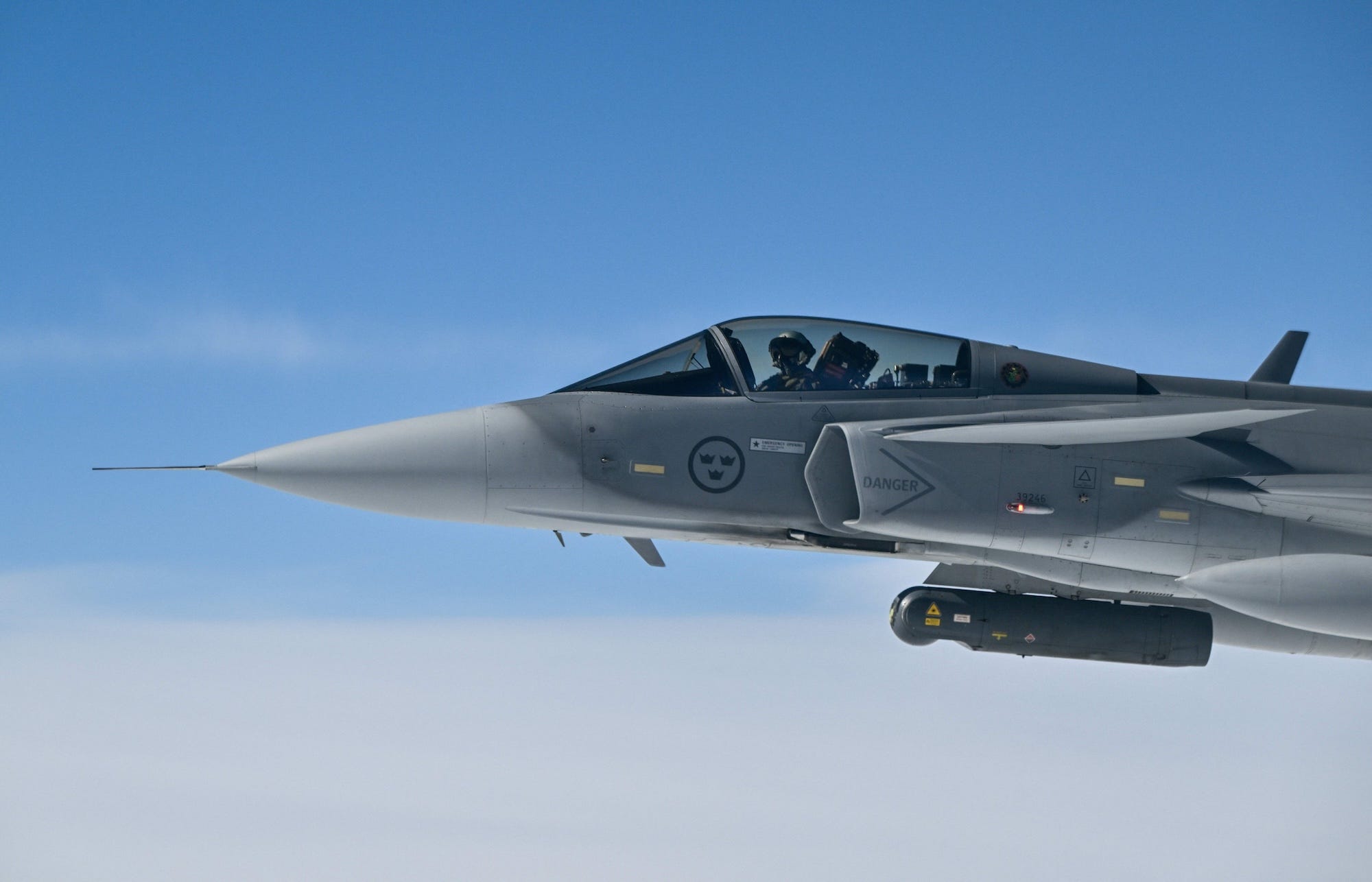 The front half of a fighter jet pictured in the air against a blue sky