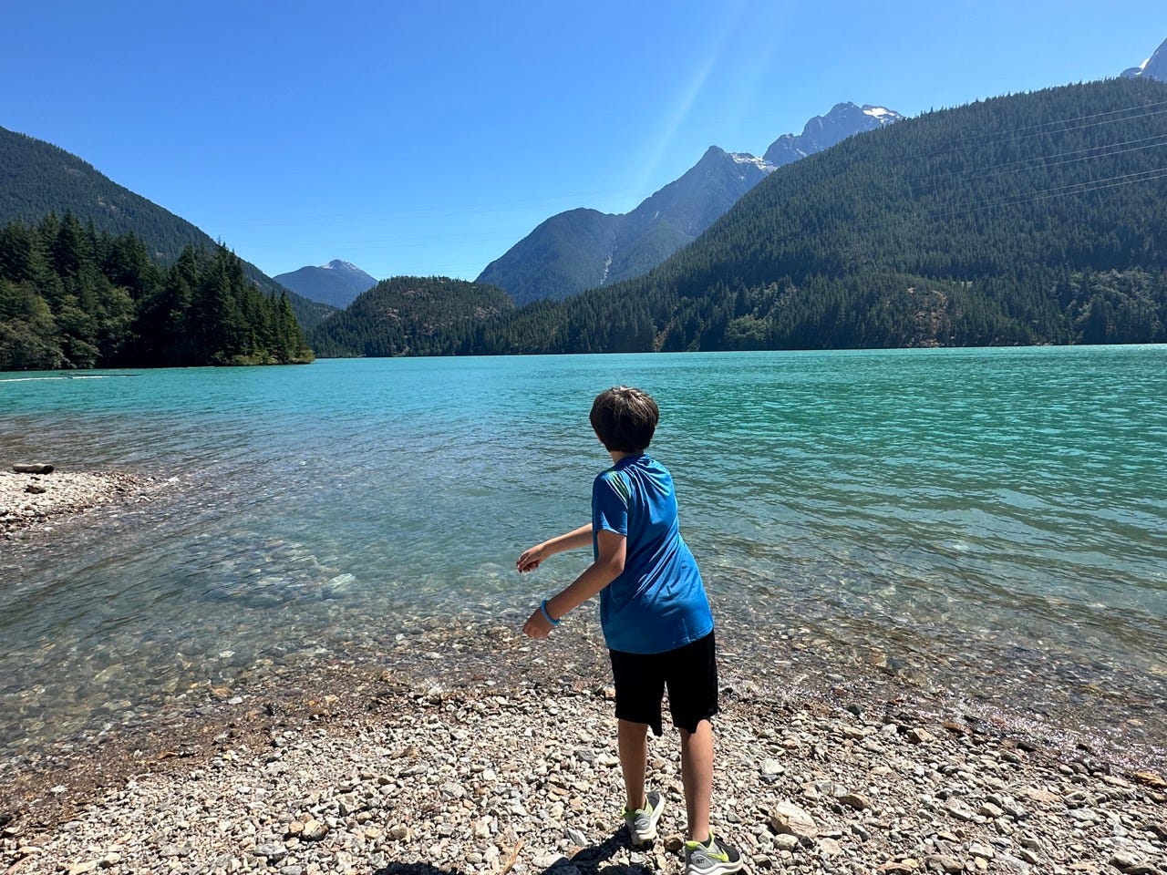 Child tossing stone into North Cascades Lake