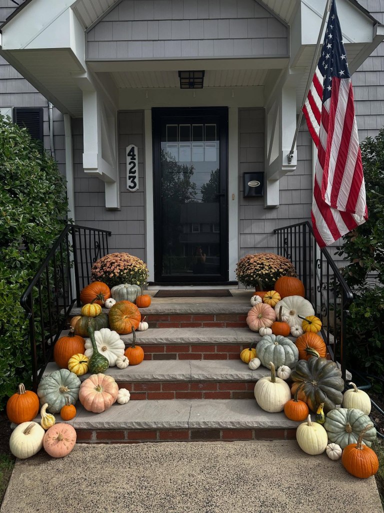 House porch decorated with pumpkins, gourds, and flowers.
