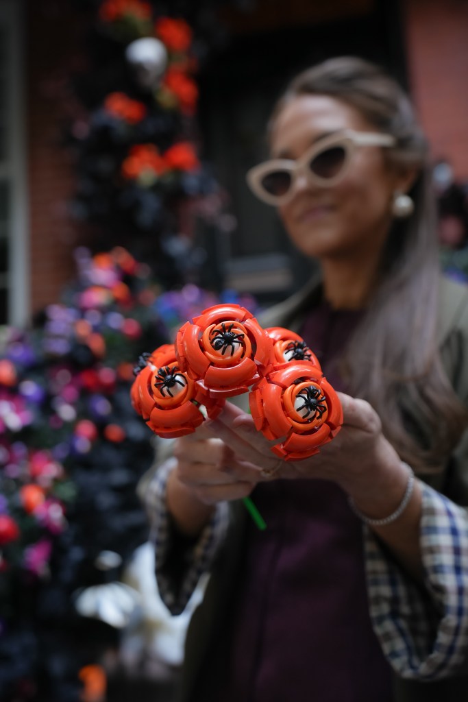 Woman holding a bouquet of Halloween-themed Lego flowers with spiders.