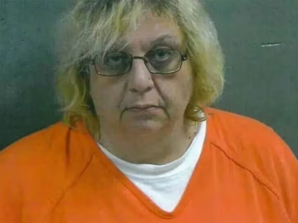 Mugshot of Marcy Oglesby wearing an orange prison uniform and glasses.