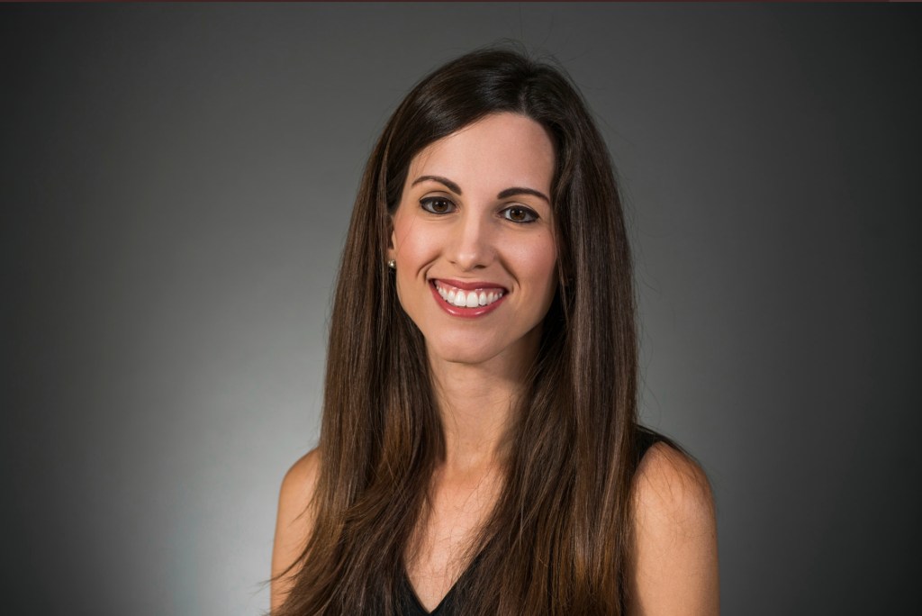 Headshot of a smiling woman with long brown hair.