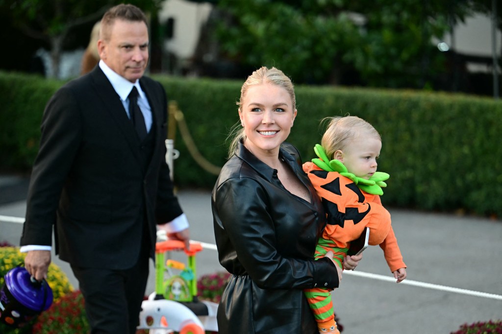 White House Press Secretary Karoline Leavitt holding a child dressed in a pumpkin costume during a Halloween event.