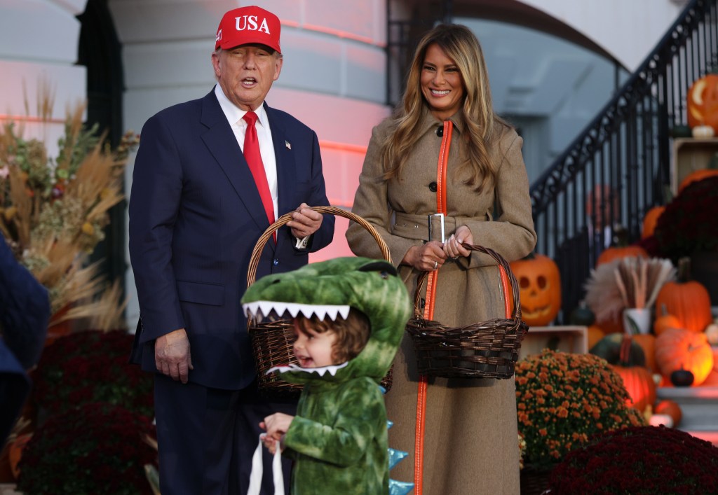 Donald and Melania Trump with a child in a dinosaur costume at a Halloween event.