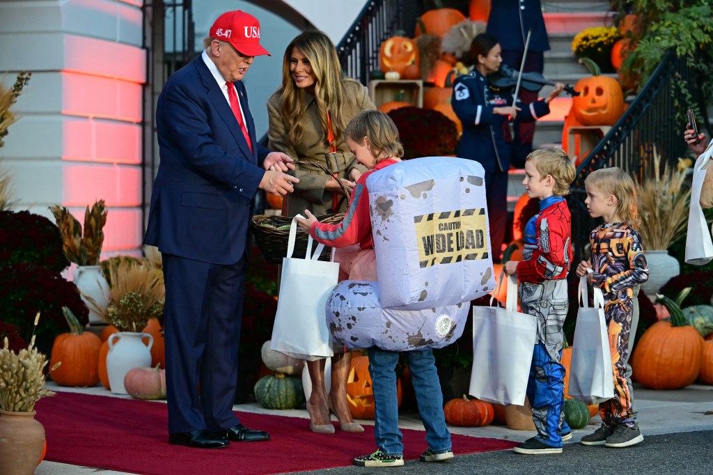 Donald Trump and Melania Trump distributing candy to costumed children at a Halloween event.
