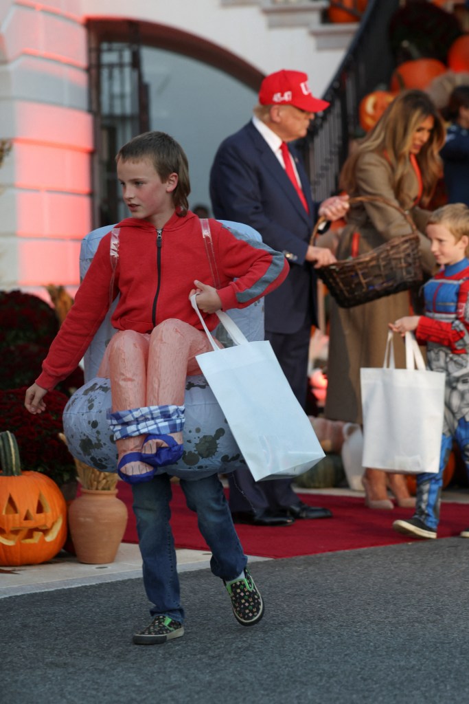 A child in an inflatable costume with fake legs holding a bag at a Halloween event.
