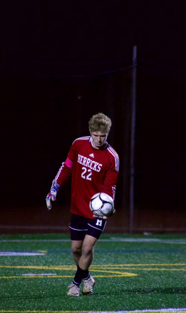 Herricks goalkeeper Brayden Haase holding a soccer ball on a field.