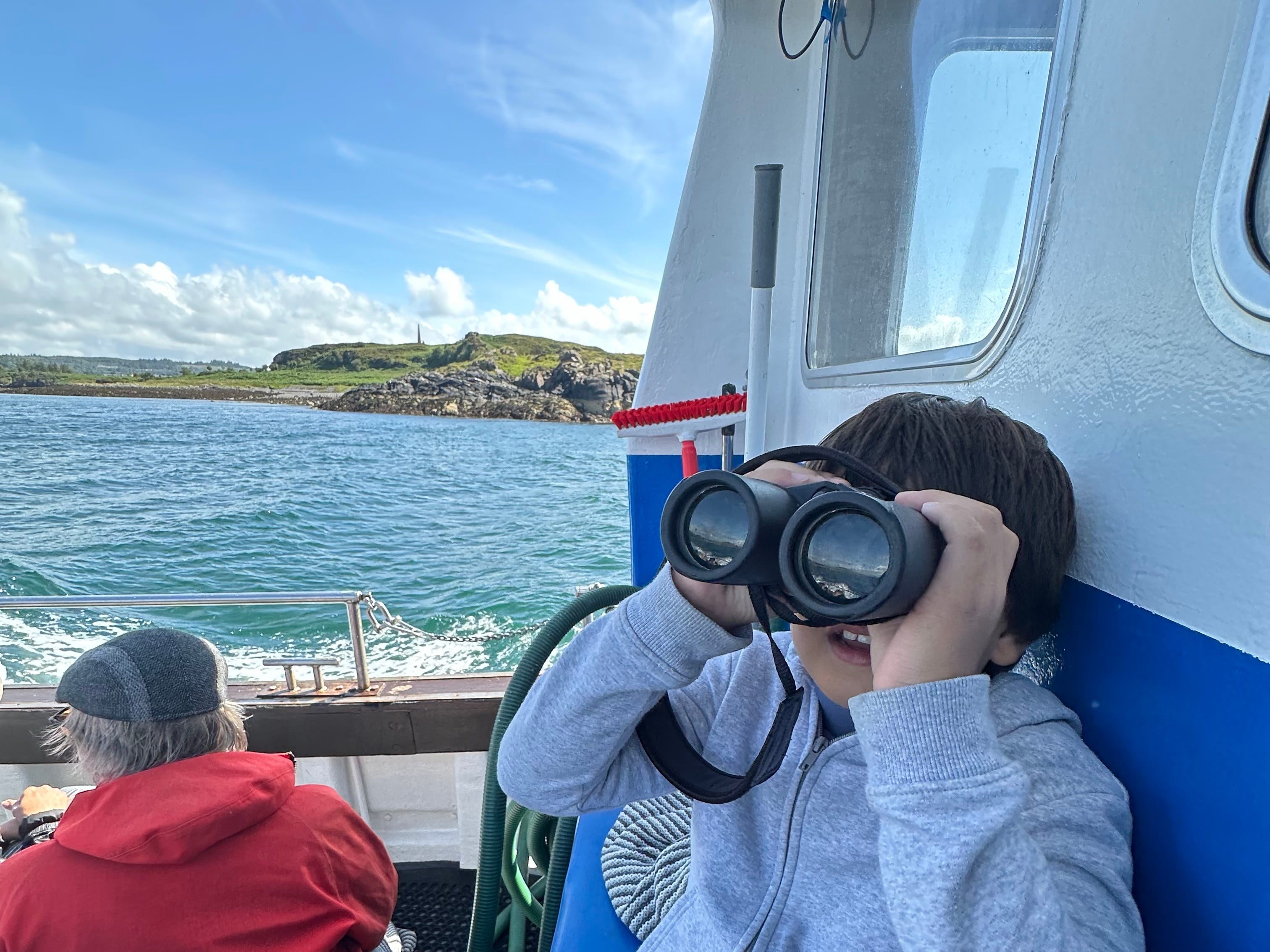 A boy looking through binoculars on a dolphin-spotting trip in Scotland.